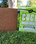 Coco Coir Mega Brick Premium Organic Coconut Coir Block 11 Lb 5 Kg, shown as a packaged block on grass in a garden setting.