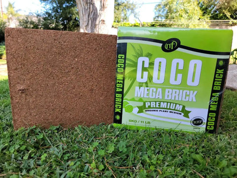 Coco Coir Mega Brick Premium Organic Coconut Coir Block 11 Lb 5 Kg, shown as a packaged block on grass in a garden setting.
