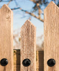 Solid 12 Pack Iron Clavos 1.5 Inches Long Featuring Gritty Hammered Black Finish applied to rustic wooden fence.