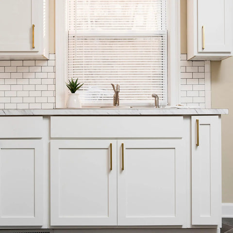 Solid Core Kitchen Cabinet Pulls In Brushed Golden Brass, 12 Inch Hole Center, on white cabinets in a kitchen setting.
