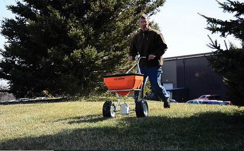 Man using Heavy Duty 70 Pound Spreader with Stainless Steel Frame on grassy lawn, showcasing precision and accuracy, sturdy design.