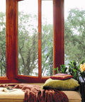 Cozy window seat with pillows, blanket, and view of trees.