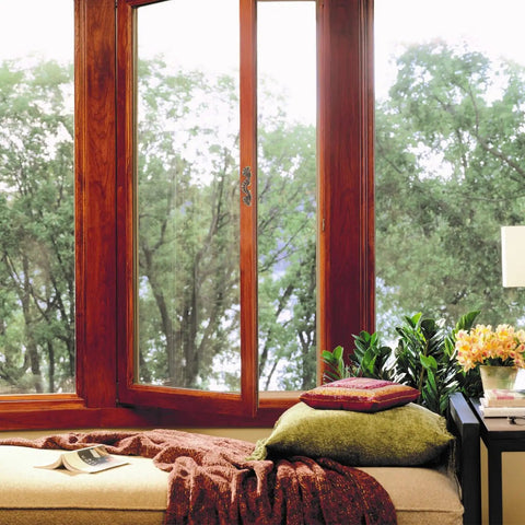 Cozy window seat with pillows, blanket, and view of trees.