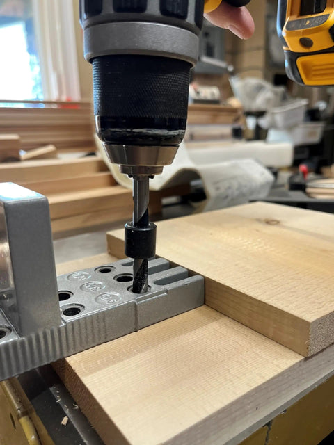 Close-up of a drill with Pro Doweling Kit with Pre-Aligned Hole Guides and Hardened Steel Bushings clamped to workbench for joints.