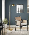 66 Inch Integrated LED Floor Lamp With Metal Shade In Brushed Brass in a modern living room setting with chair and decor