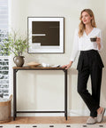 Woman stands by narrow entryway console table and sofa side table in industrial hallway style for small spaces space saver