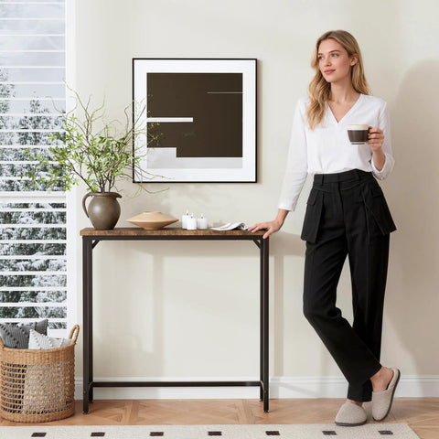 Woman stands by narrow entryway console table and sofa side table in industrial hallway style for small spaces space saver