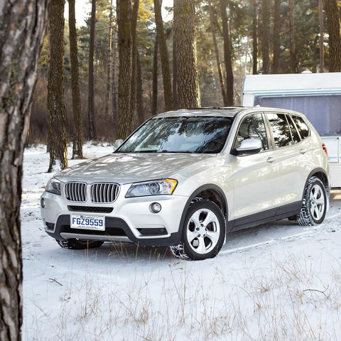 SUV with set of two four hole license plate frames in slim stainless steel with a polished mirror finish and chrome screw caps in snowy forest