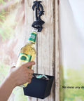 Heavy Duty Black Palm Tree Wall Mounted Beer Bottle Opener With Rugged Cap Catcher Bucket in use, capturing bottle caps.
