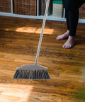 Dark Grey Angle Floor Broom With Long Stainless Steel Handle And Dense Stiff Bristles snags pet hair on hardwood floor.