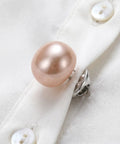 Close-up of a pink faux pearl brooch pin on a white shirt, part of 25Pcs No Sew Faux Pearl Brooch Pins Detachable Sweater Clips Reusable Shirt Fasteners Your New Go To Wardrobe Lifesaver For Hassle Free Snug Security On Every Fit You Own.
