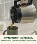 Coffee being poured from PerfecTemp Thermal Carafe of 12 Cup Programmable Coffee Maker into mug, shown on kitchen counter.