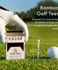 Gloved hand holding 24 Piece Premium Bamboo Golf Tees 83mm 3.25 Inches With Vintage Carry Case, golf ball on grass