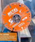 Front view of an orange 4-inch diamond metal cutting wheel with 7/8-inch arbor mounted on a grinder.