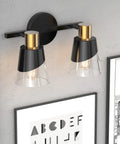 Over Mirror Vanity Light Fixture With Black And Gold Finish 2 Light Wall Lamp with beveled edge clear glass shades mounted on wall.