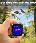 Hand holding a pocket sized thermal camera with touchscreen displaying infrared image in a forest, detecting hidden birds.