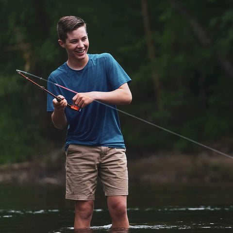 Smiling person fishing with All In One Fly Fishing Kit With Eight Foot Five To Six Weight Three Piece Rod Rim Control Reel in river
