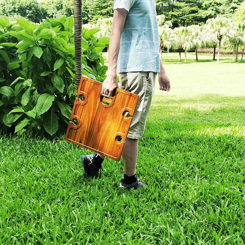 Person holding Portable Wine Picnic Table in Acacia Wood With Larger Foldable Tray Charcuterie Board Surface on grass