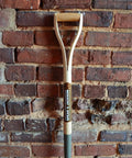 Heritage Forged Digging Fork With Solid Carbon Steel Head And Wishbone Handle against brick wall