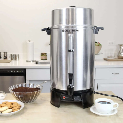 100 Cup Commercial Coffee Urn With Automatic Temperature Control Fast Brewing Easy Clean Up NSF Approved Large Capacity Keeps Joe Hot All Day Silver For Large Events, shown on a countertop with coffee and snacks.