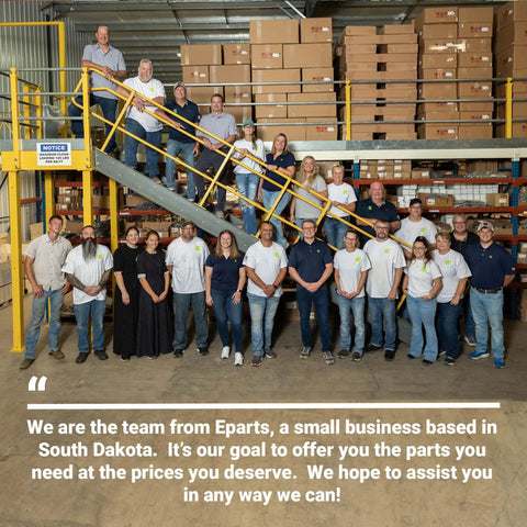 Group of employees at Eparts, standing in a warehouse with shelves of boxes behind them, team from South Dakota