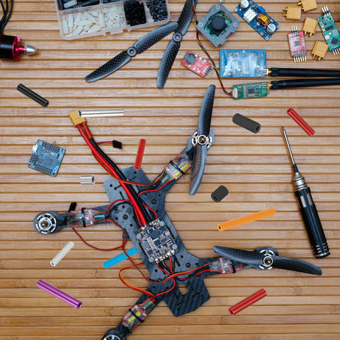 Quadcopter drone frame with carbon fiber arms, motors, and wiring on a wooden workbench.