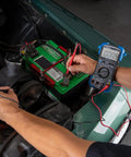 Person using Pro Grade Automotive Digital Multimeter With Auto Range And Overload Protection Measures Up To 15 Amps 10 MOhm Input Impedance Auto Shutoff Tests Diodes Duty Cycle Solenoids Wiring And Switches For Engine Diagnostics on car battery