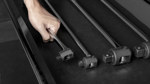 Hand holding Extended 18 Inch Three Eighths Inch Drive Breaker Bar with Heavy Duty Chrome Vanadium Shaft on tool shelf