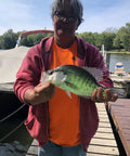 Person holding a large crappie fish near a dock on a sunny day