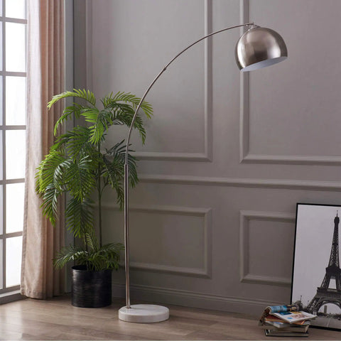 Arc Floor Lamp With Faux White Marble Base And Nickel Bell Shade For Living Rooms Offices Bedrooms Sleek Modern Mid Century Vibe Warm Ambient Task Lighting in a modern living room setting next to a potted plant.
