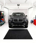 Heavy Duty Garage Oil Spill Mat 60 By 72 Inch in front of parked car in garage, showcasing its slip-resistant, waterproof backing.