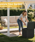 Outdoor 31 Gallon Storage Box With Lid for patio furniture organization under gazebo with woman placing cushions inside