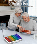 Pill organizer with seven rainbow-colored weekday compartments and clear lid.