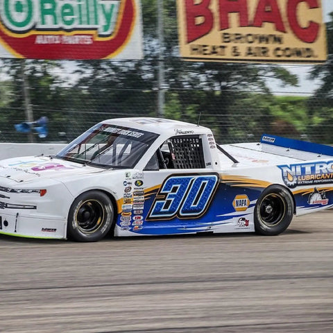 Racing truck on track with Nitro Lubricants branding and sponsors, showcasing automotive performance applications of the product.