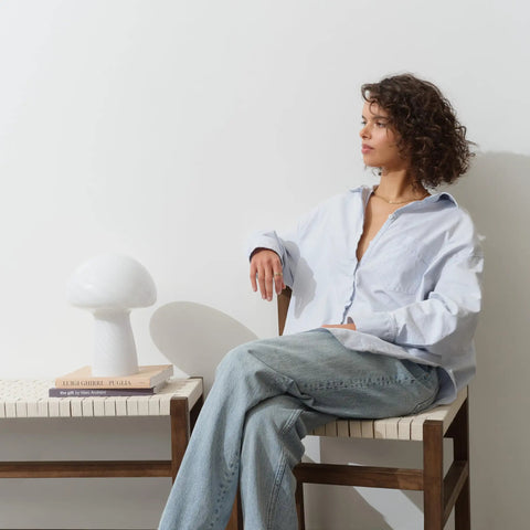 Mushroom Glass Table Lamp 12.75 Inch For Bedside Tables And Desks next to a person seated, emitting warm white glow on a modern chair.