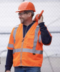 Two workers wearing High Visibility Sleeved Mesh Safety Vest With Brilliant Reflective Tape And Utility Pockets Class 3, smiling on site.