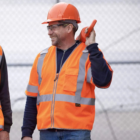 Two workers wearing High Visibility Sleeved Mesh Safety Vest With Brilliant Reflective Tape And Utility Pockets Class 3, smiling on site.