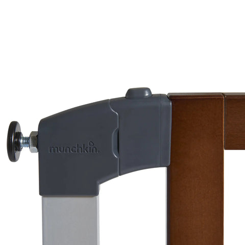 Close-up of Auto Close Modern Pressure Mounted Baby Gate For Stairs, Hallways And Doors, featuring dark wood and silver metal latch.