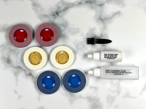 Motorized Disc Cleaning And Repair Kit for Blu Ray DVD and CD with pads, brush, and cleaning fluids on marble surface.