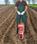 Walk Behind Garden Seeder With Six Nozzles Handy Manual Push Planter in use on farm soil, man in green overalls and gloves