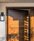 Capulet Amber Glass Center Column Outdoor Indoor Wall Sconce With LED Black Finish beside a wooden door entryway