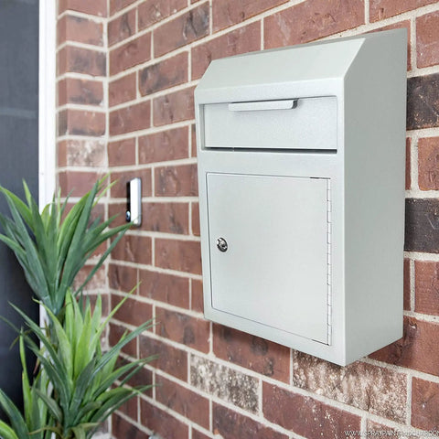 Wall-mounted locking key drop box with tubular lock and baffle on brick wall, large mail slot for secure deposits in offices.