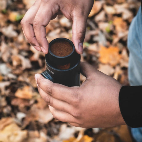 Person handling Nanopresso Portable Espresso Maker With 18 Bar Pressure Manual Battery Free Travel Coffee Kit For Rich Crema On The Go Evolution From Minipresso Compact Grey outdoors.