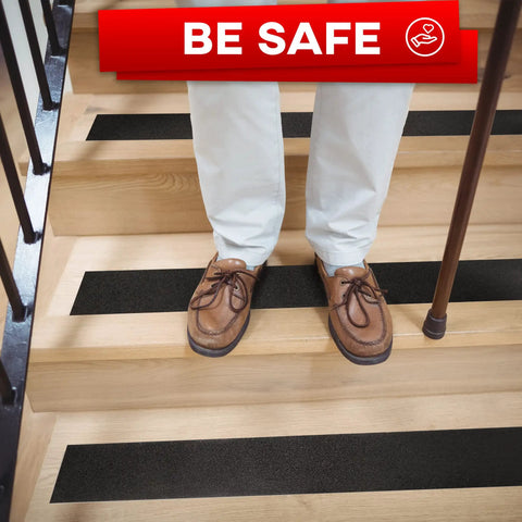 Man standing on wooden steps with Heavy Duty Anti Slip Tape For Stairs Indoor Outdoor Waterproof 4 Inch By 35 Ft Non Skid Adhesive Roll in black.