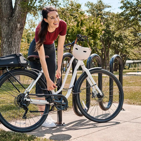 Woman securing bike with Bike Cable Lock 6 Feet By Half Inch With Resettable Four Digit Combination And Black Vinyl Coating at rack.