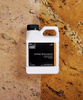 Real Deal Stone Enhancer And Penetrating Sealer That Levels Up Marble And Granite Water Based Formula in a 1 pint bottle on stone surface.