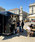 Slick 12 Foot Black Stainless Steel Commercial Food Trailer Equipped With Turnkey Mobile Beer Bar Station And Tough Catering Gear For A No Fuss Pop Up Hustle in a busy outdoor setting.