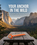 Beefy Ground Anchors For Heavy Duty Screw In Tent Stakes Built For High Wind And Loose Sand Perfect For Canopies, Shade Shelters, RV Awnings, Dogs, Trampolines, And More With T Grip Tool Included Two Pack, displayed on a wooden table against a mountain backdrop.