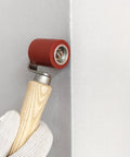 Side view of handheld 40mm red silicone seam roller with wooden handle for wallpaper roofing tape
