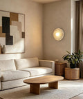 MECOLA Round Resin Accent Wall Sconce Small Glass Globe Shade Wall Lamp illuminated on wall above a light-colored couch in living room.